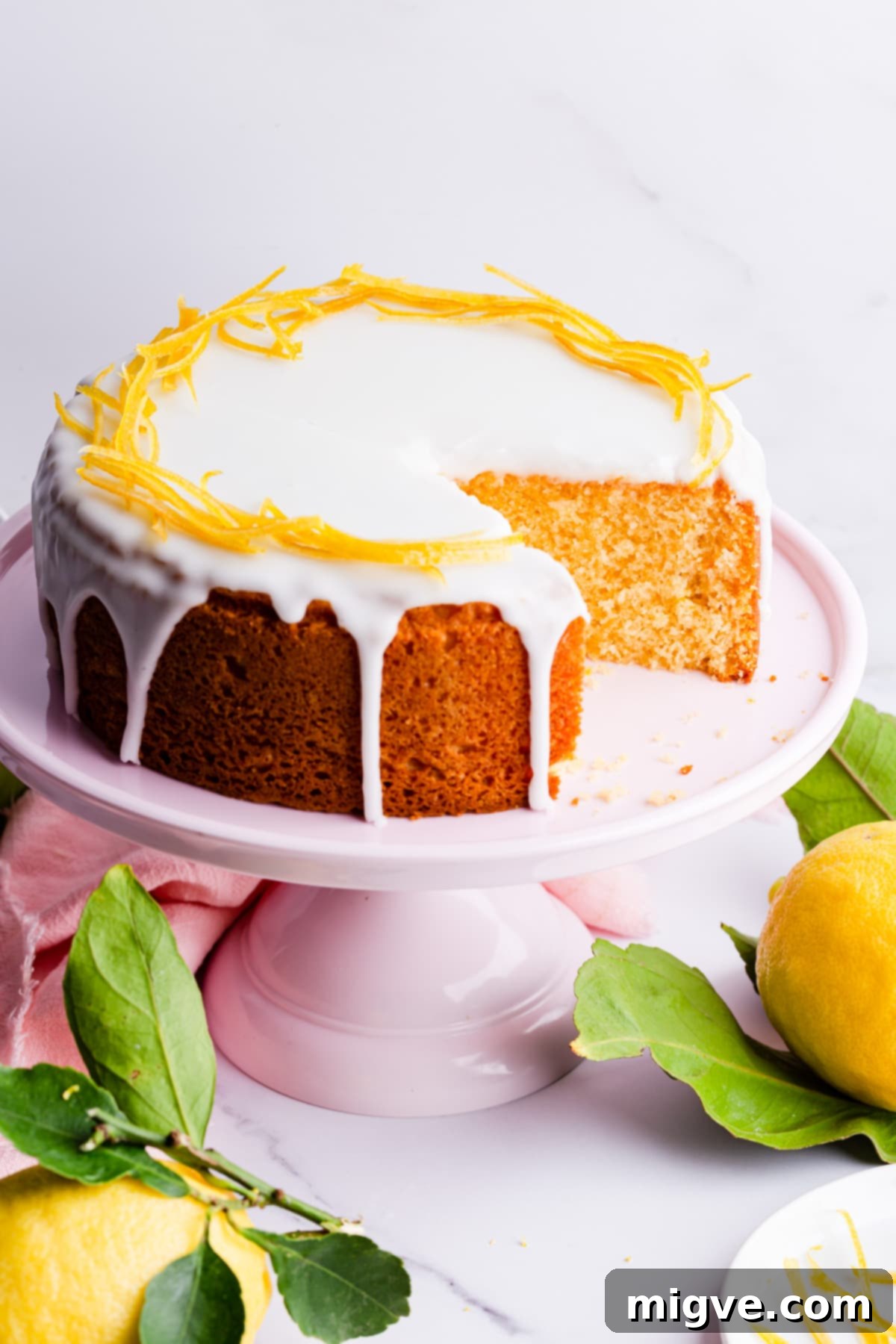 A citrus cake with white icing, with a slice removed to show the moist interior.