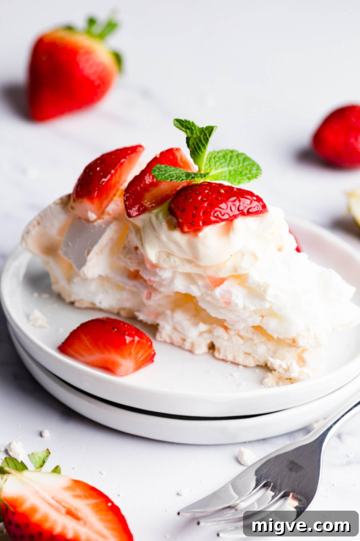Close-up side view of a perfect slice of pavlova meringue on a small white plate, highlighting its crisp texture and clean cut