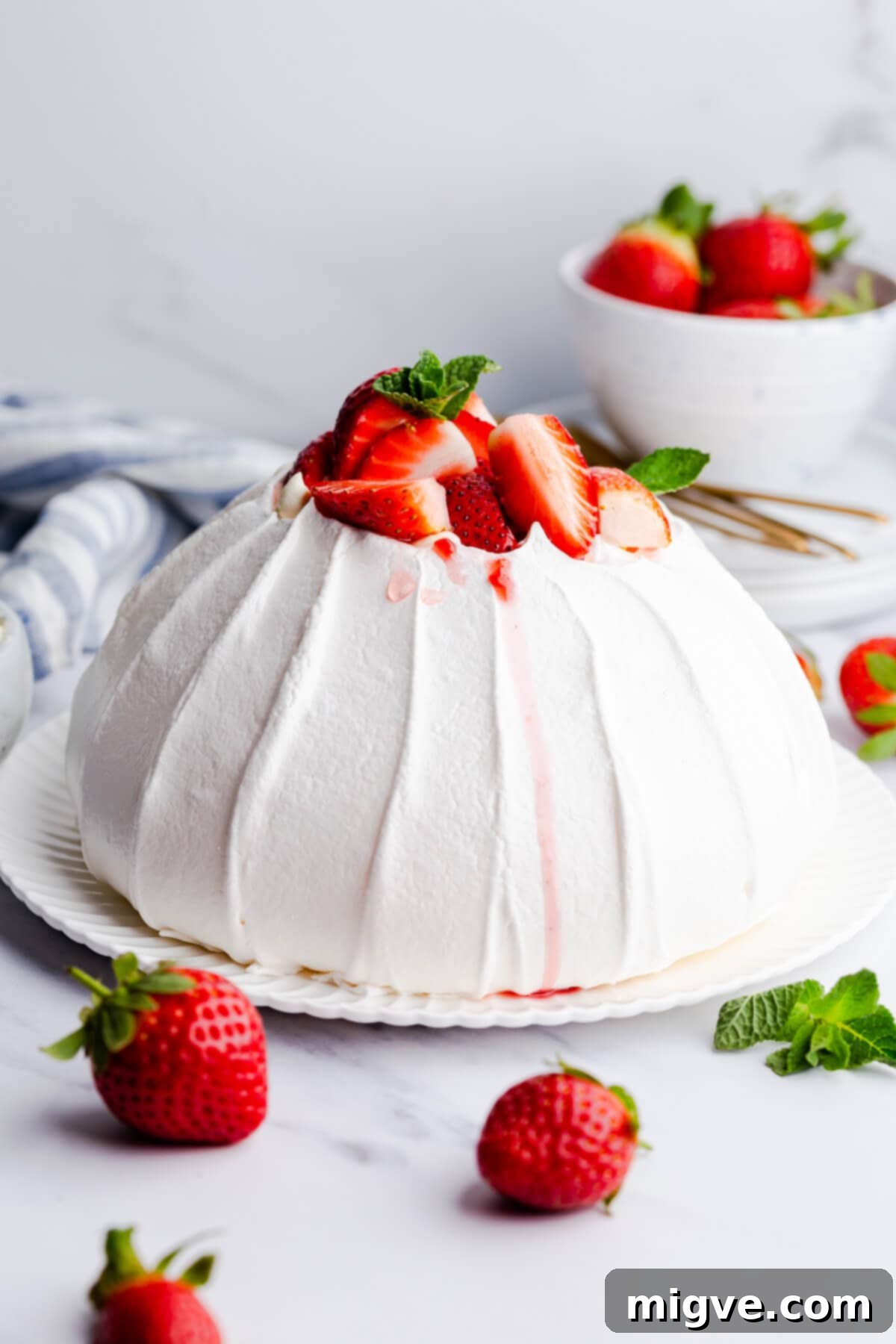 A stunning side close-up of a fully assembled strawberry pavlova, glistening with fresh fruit and cream, ready to be enjoyed