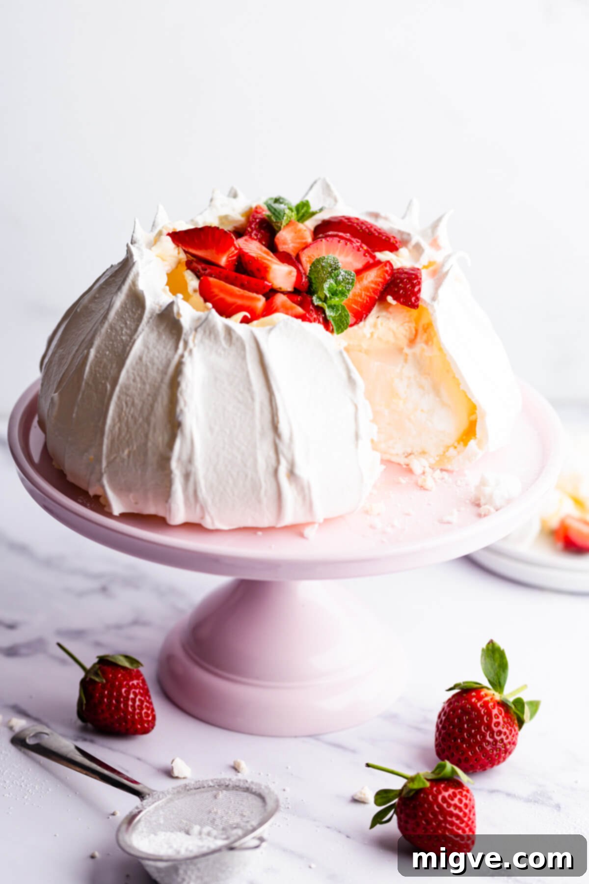 Side view of a slice of strawberry pavlova, showing its crisp exterior, soft interior, and layers of cream and fruit