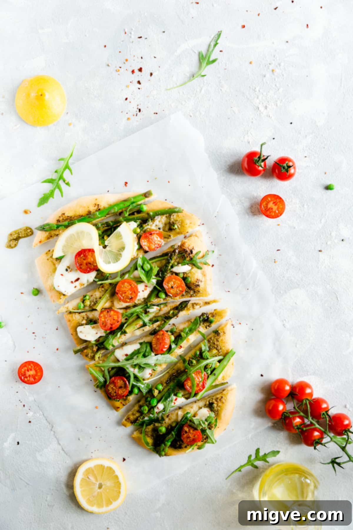 Beautiful overhead shot of a perfectly round asparagus green pesto pizza, already expertly cut into ready-to-serve slices, showcasing the vibrant array of toppings and golden crust.