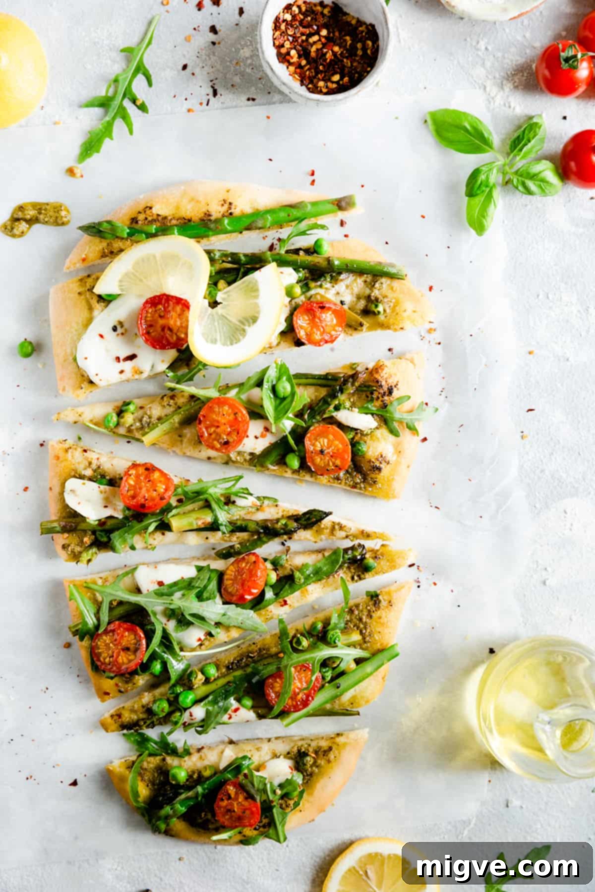 Overhead shot of a freshly baked homemade rocket and asparagus green pesto pizza, cut into perfect triangle slices, with steam gently rising, showcasing its appetizing appeal.