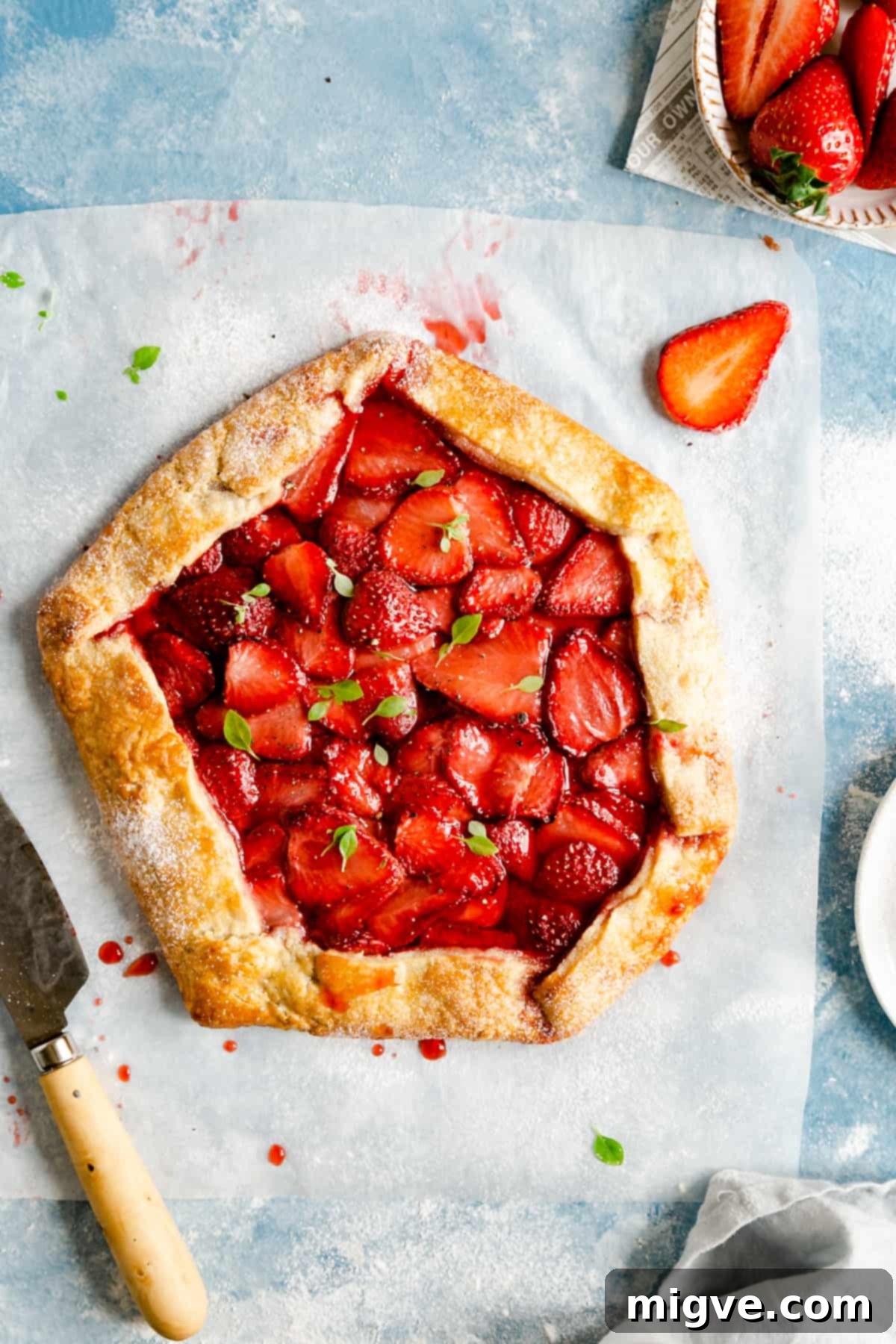 Rustic Strawberry Galette 2 overhead shot of baked strawberry galette with basil leaves scattered on top