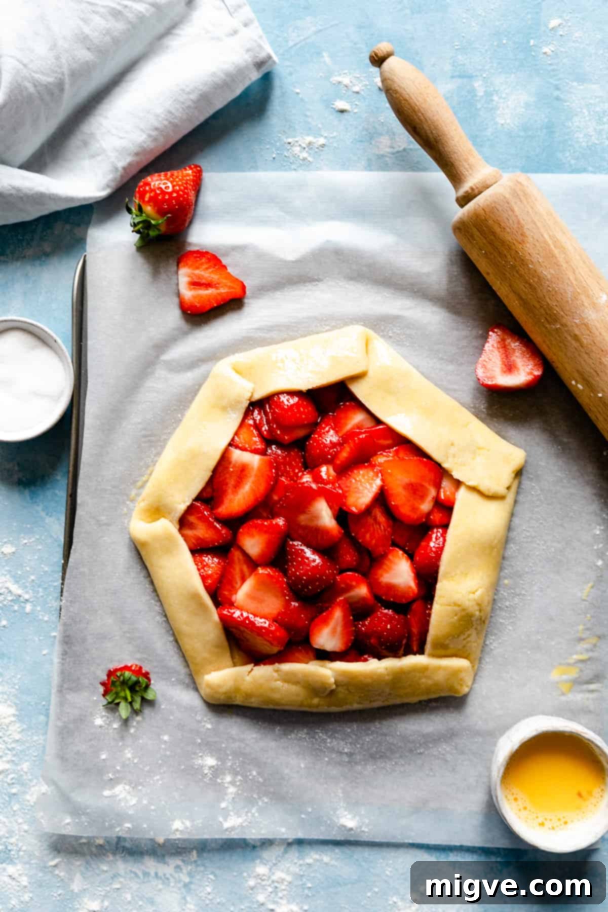 Rustic Strawberry Galette 10 top view of unbaked strawberry galette on a blue background