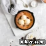 overhead shot of skillet cookie topped with 3 scoops of vanilla ice cream