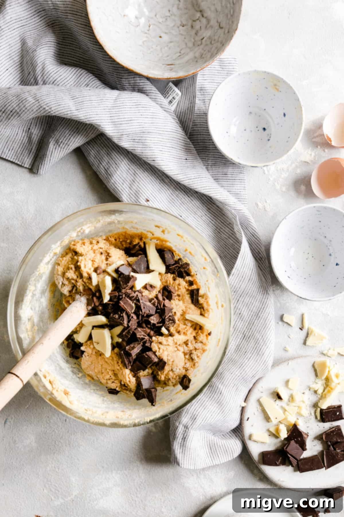 Top view of a bowl filled with rich cookie dough, generously studded with large chocolate chunks, ready for baking.