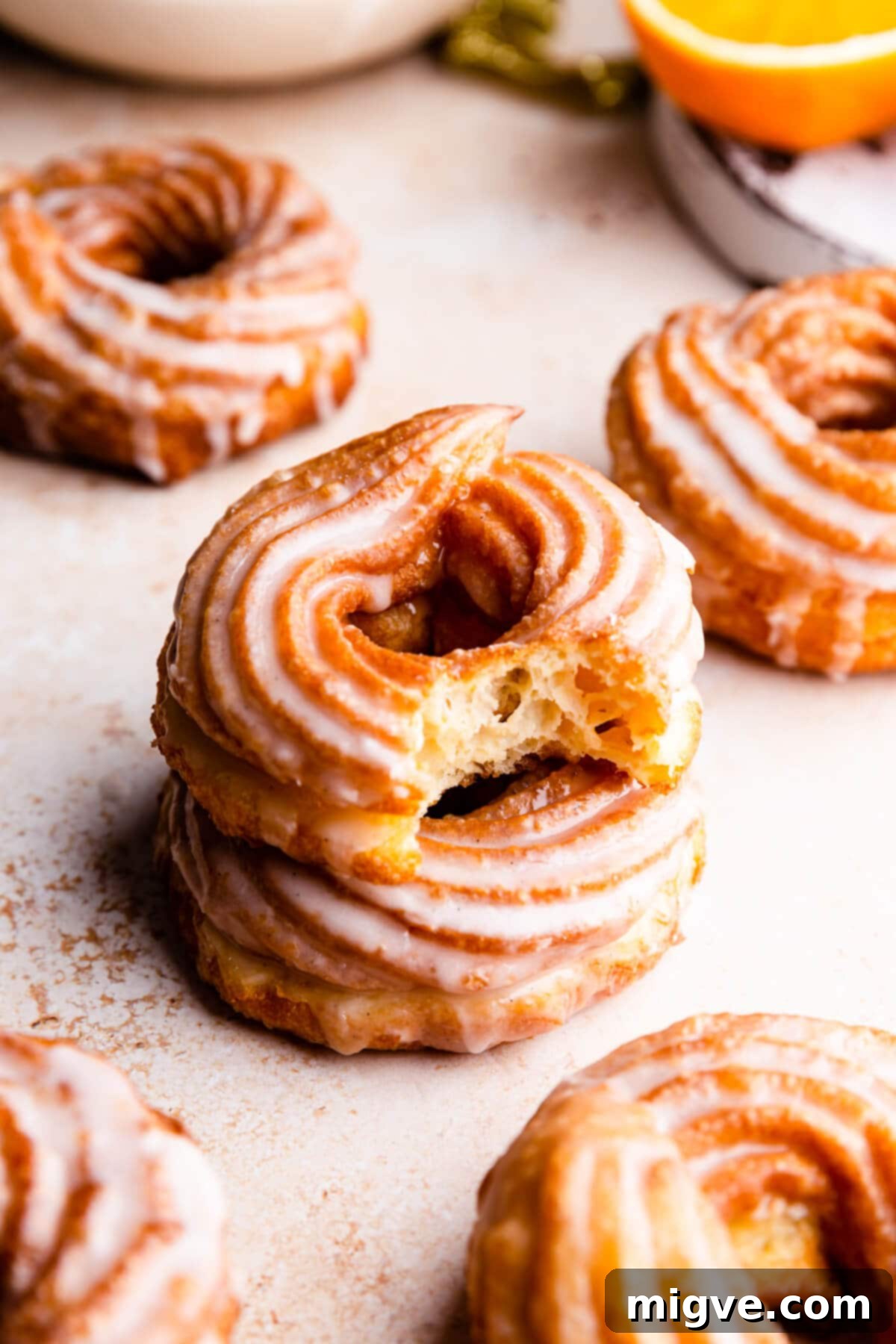 Airy Choux Rings 9 Close-up side view of a stack of two golden-brown French crullers, with the top one showing a bite taken out, revealing its airy interior.