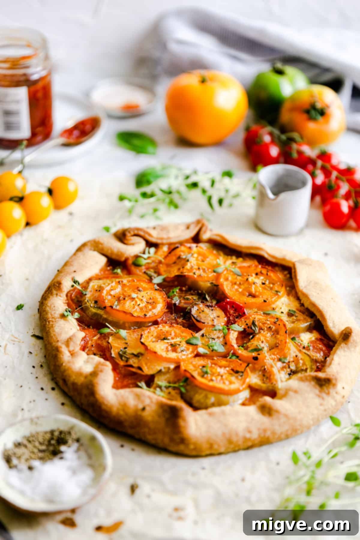 side view of a freshly baked summer tomato galette, showcasing its golden crust and vibrant tomato filling
