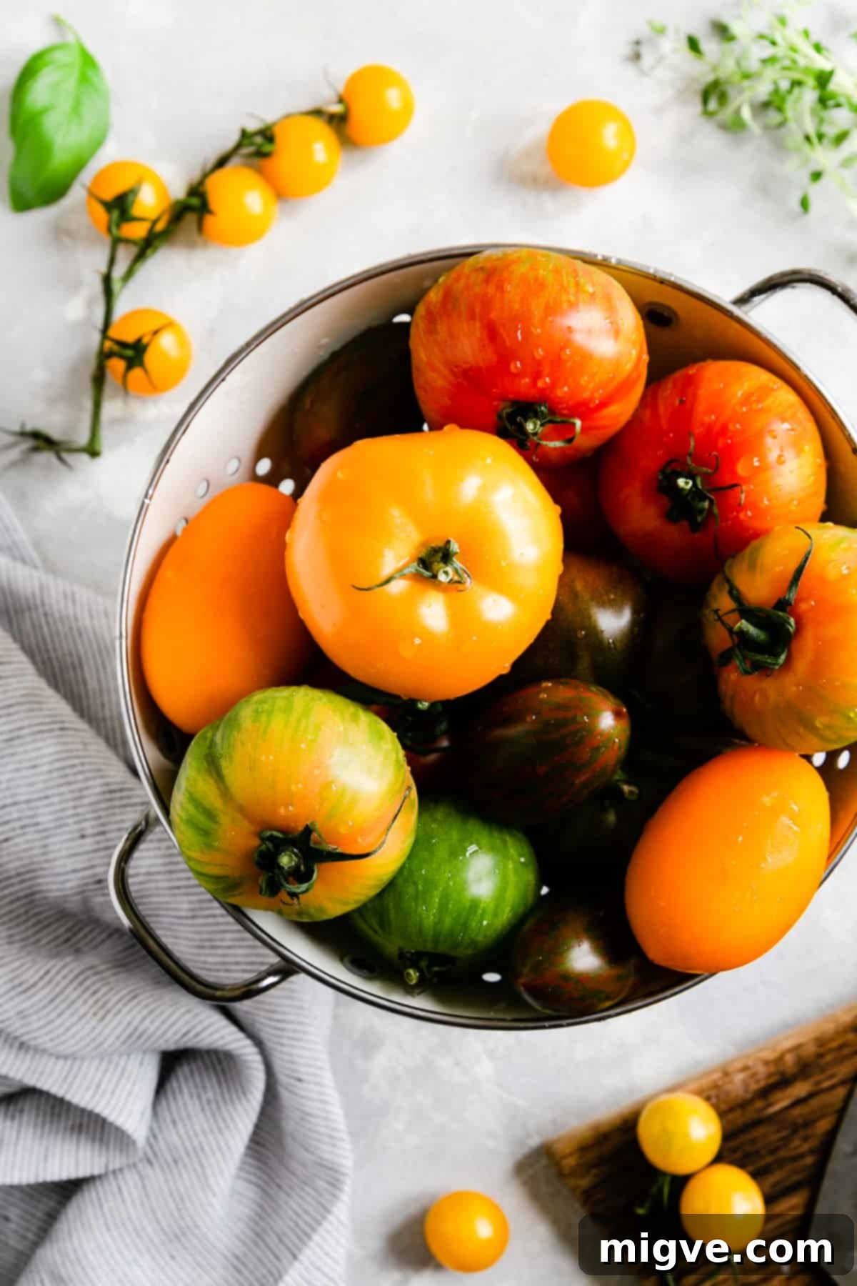 top view of a rustic colander brimming with an assortment of colourful, ripe tomatoes, perfect for a summer galette