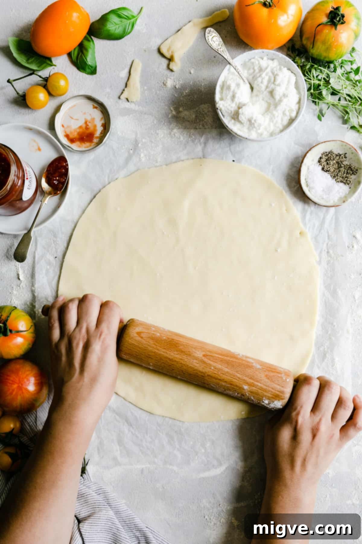 overhead shot of a skilled cook gracefully rolling out pastry dough into a large, even circle on a floured surface