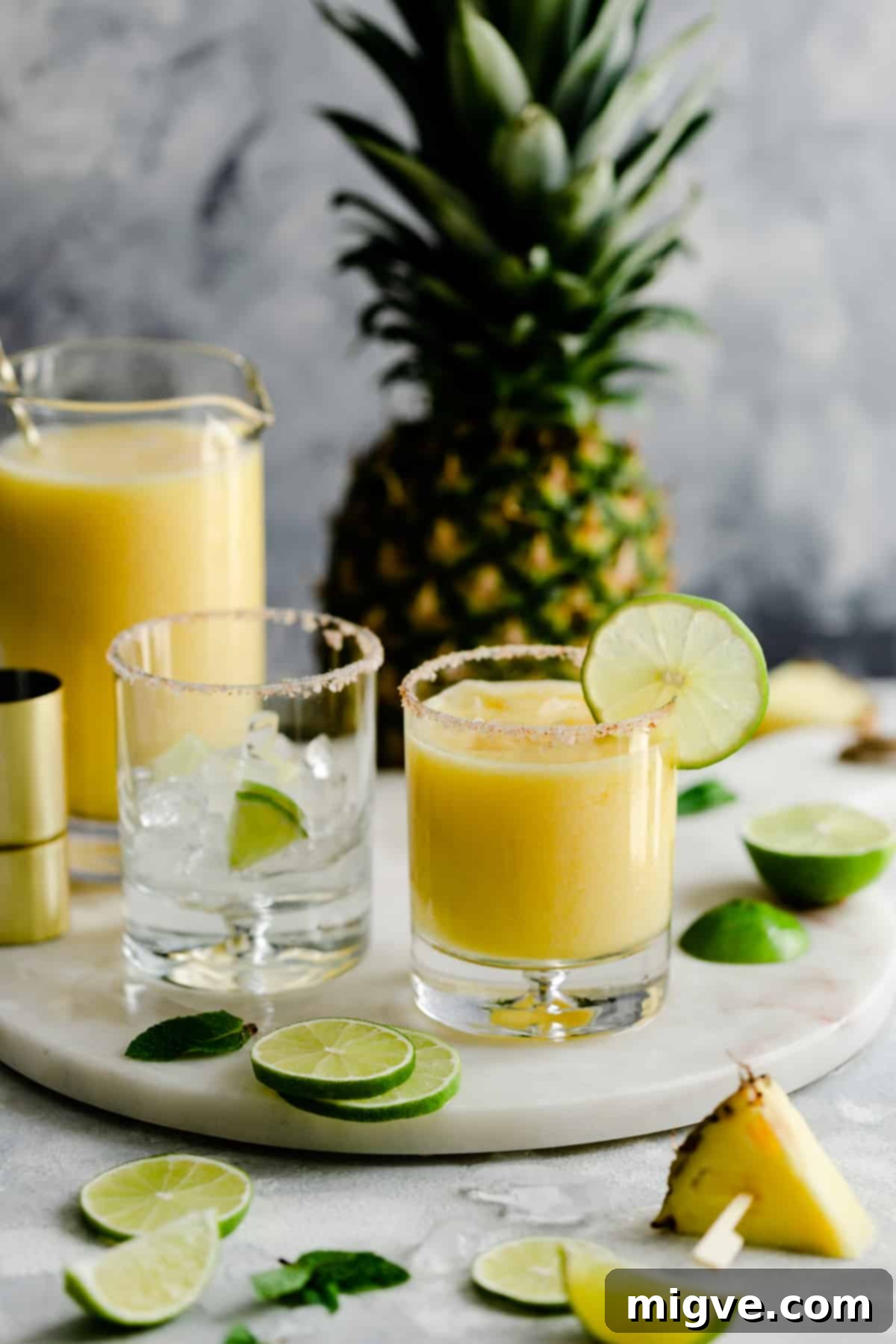A short, elegant glass holding a frozen pineapple margarita, resting on a sophisticated marble board.
