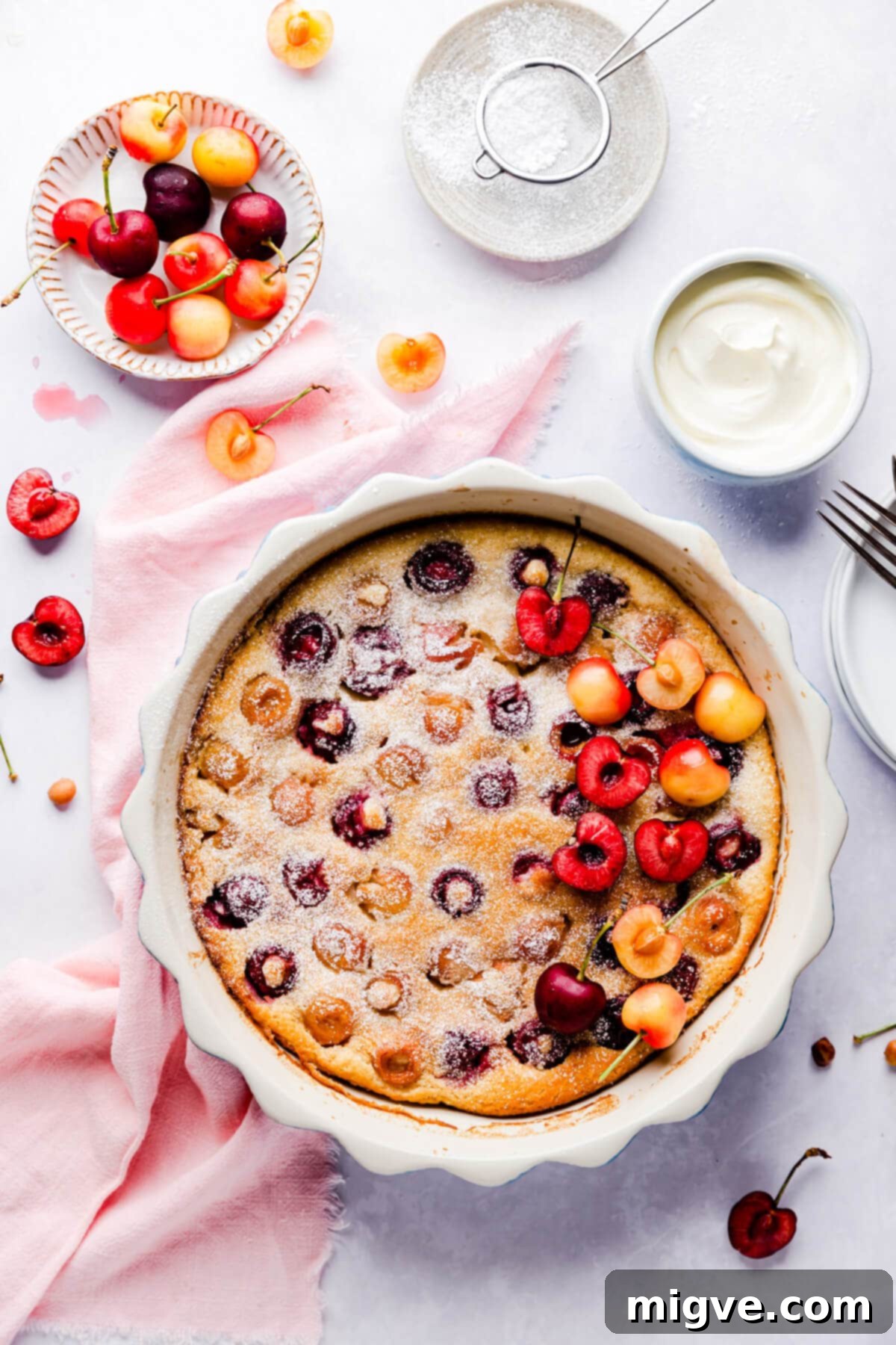 Cherry clafoutis in a baking dish with some fresh cherries on side