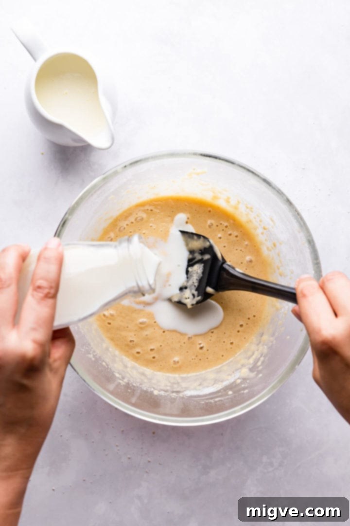 overhead view of milk being poured into the bowl with cake batter