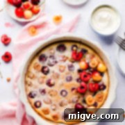 Overhead view of baked clafoutis in a baking dish topped with fresh cherries