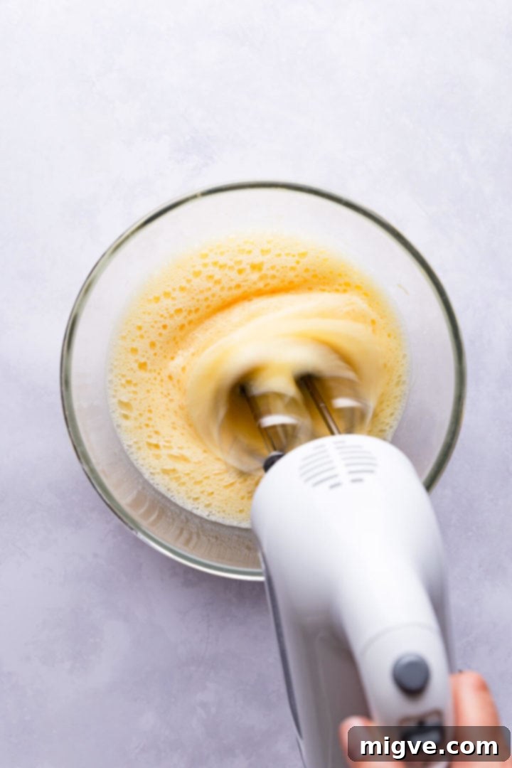 overhead view of eggs being beaten in a bowl with an electric mixer