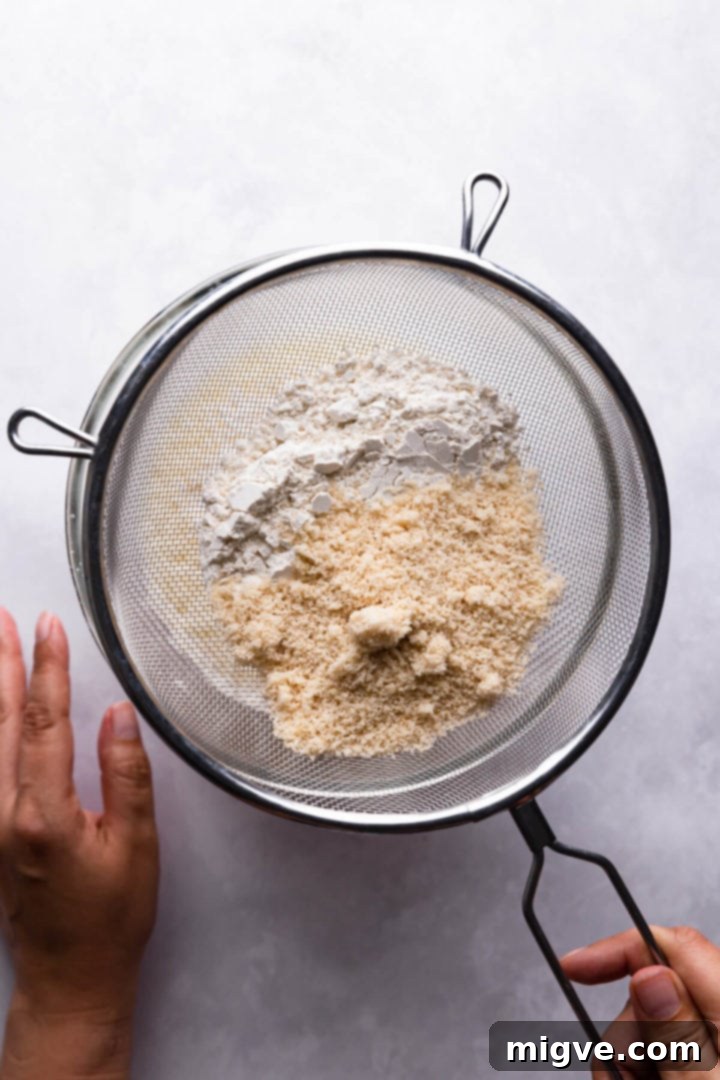 overhead view of a person sieving flour into bowl