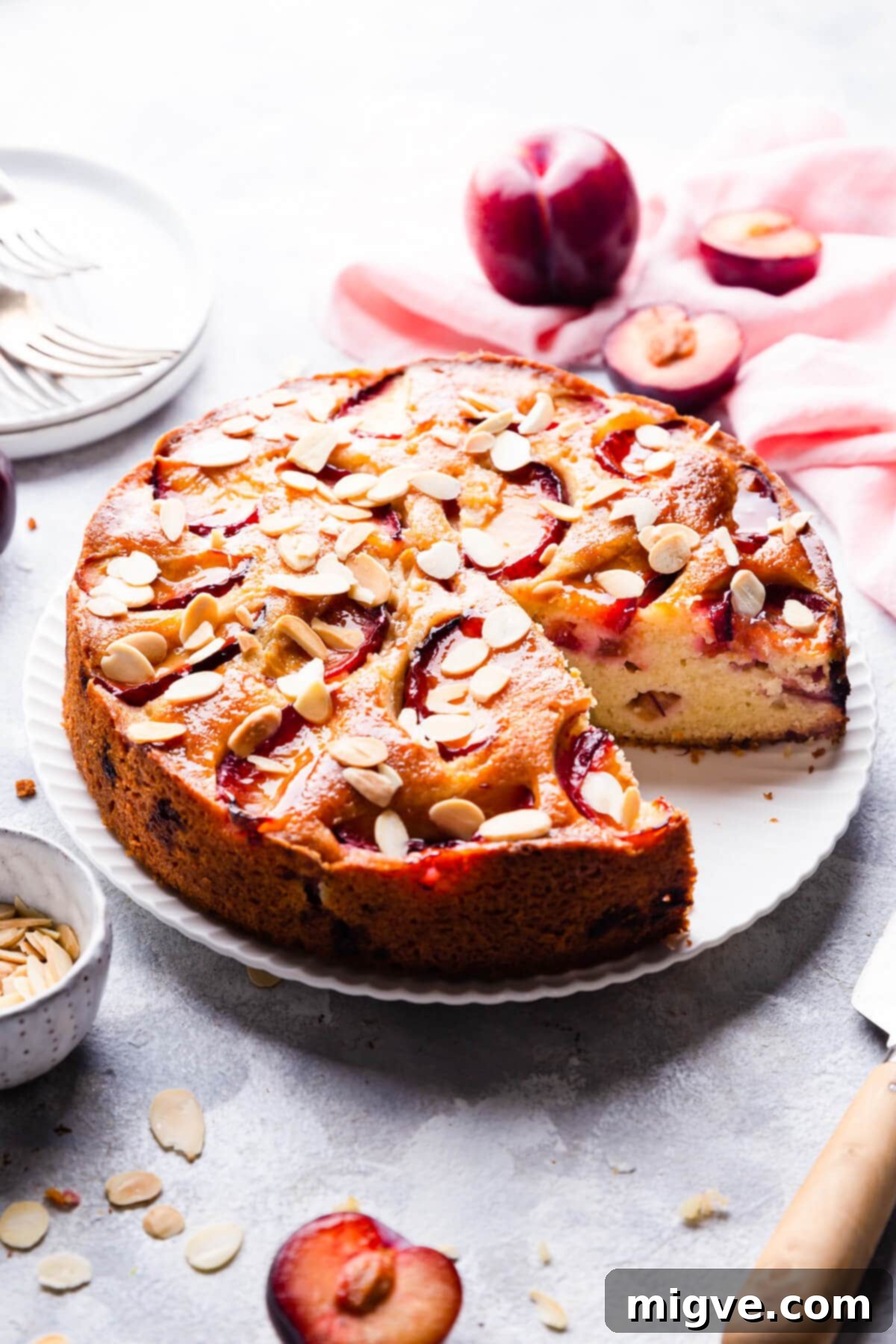 45 degree angle view of plum and almond cake with a slice cut out, ready to be served