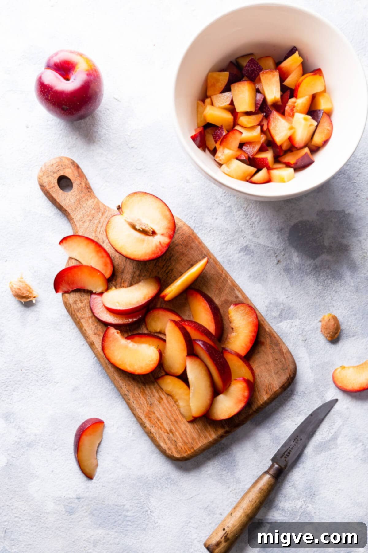 overhead shot of fresh plums, some cut into wedges and some chopped, ready for baking
