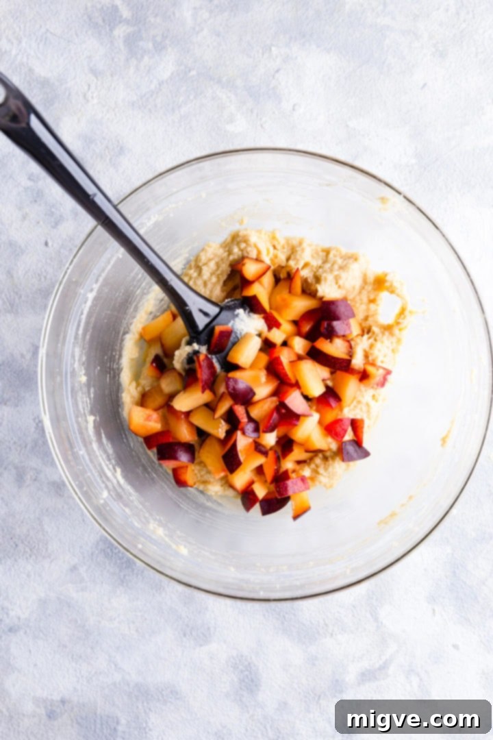 top view of the mixing bowl with cake batter and chopped plums