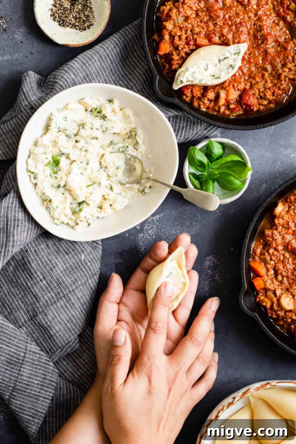overhead shot of a person stuffing pasta shells with cheese, close up