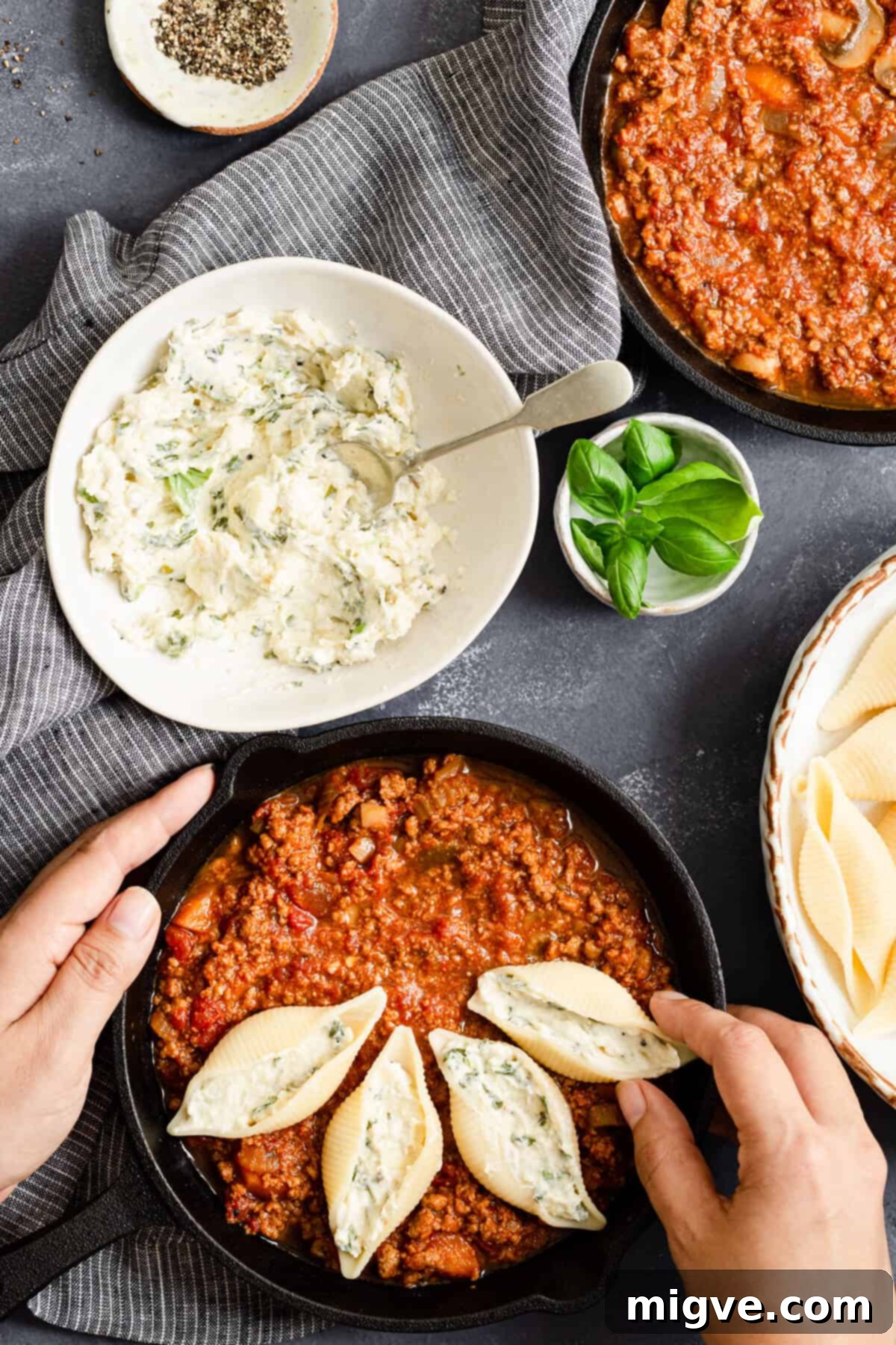 top view of pasta shells being neatly arranged in the pan with bolognese