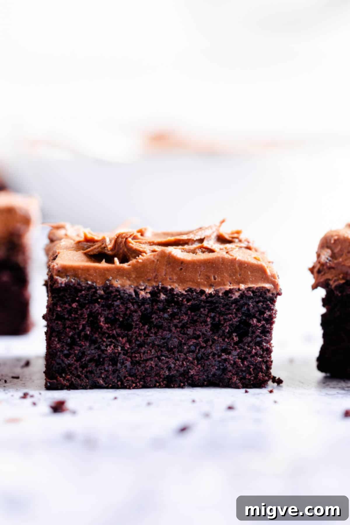Close-up side view of a perfect slice of dark chocolate traybake, showcasing the moist cake texture and thick, smooth buttercream.