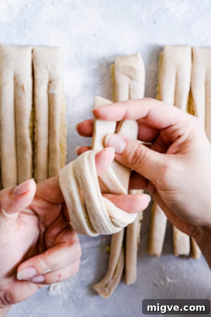 Close-up of a person's hands delicately shaping the dough into a perfect knot for a cardamom bun.