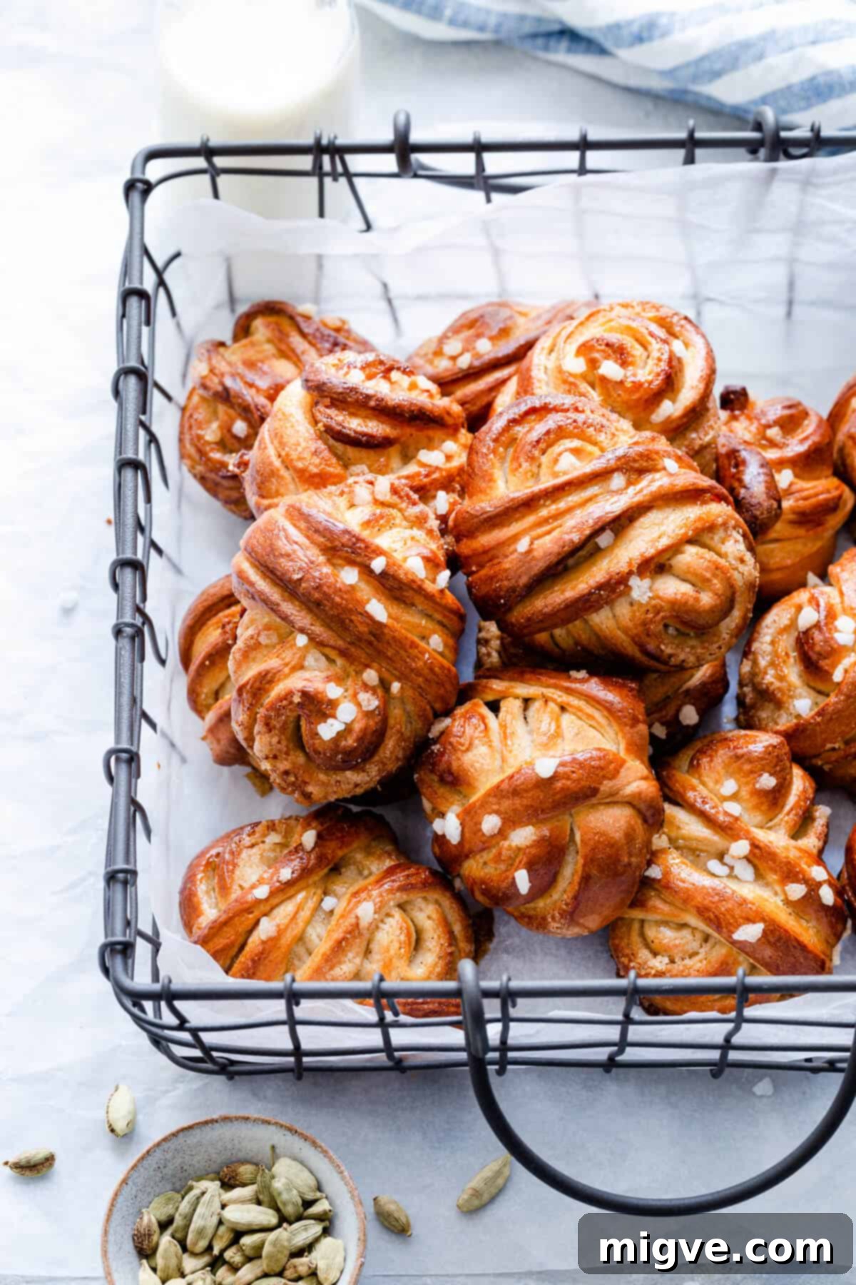 A close-up side view of baked cardamom buns arranged in a rustic wired basket, ready for serving.