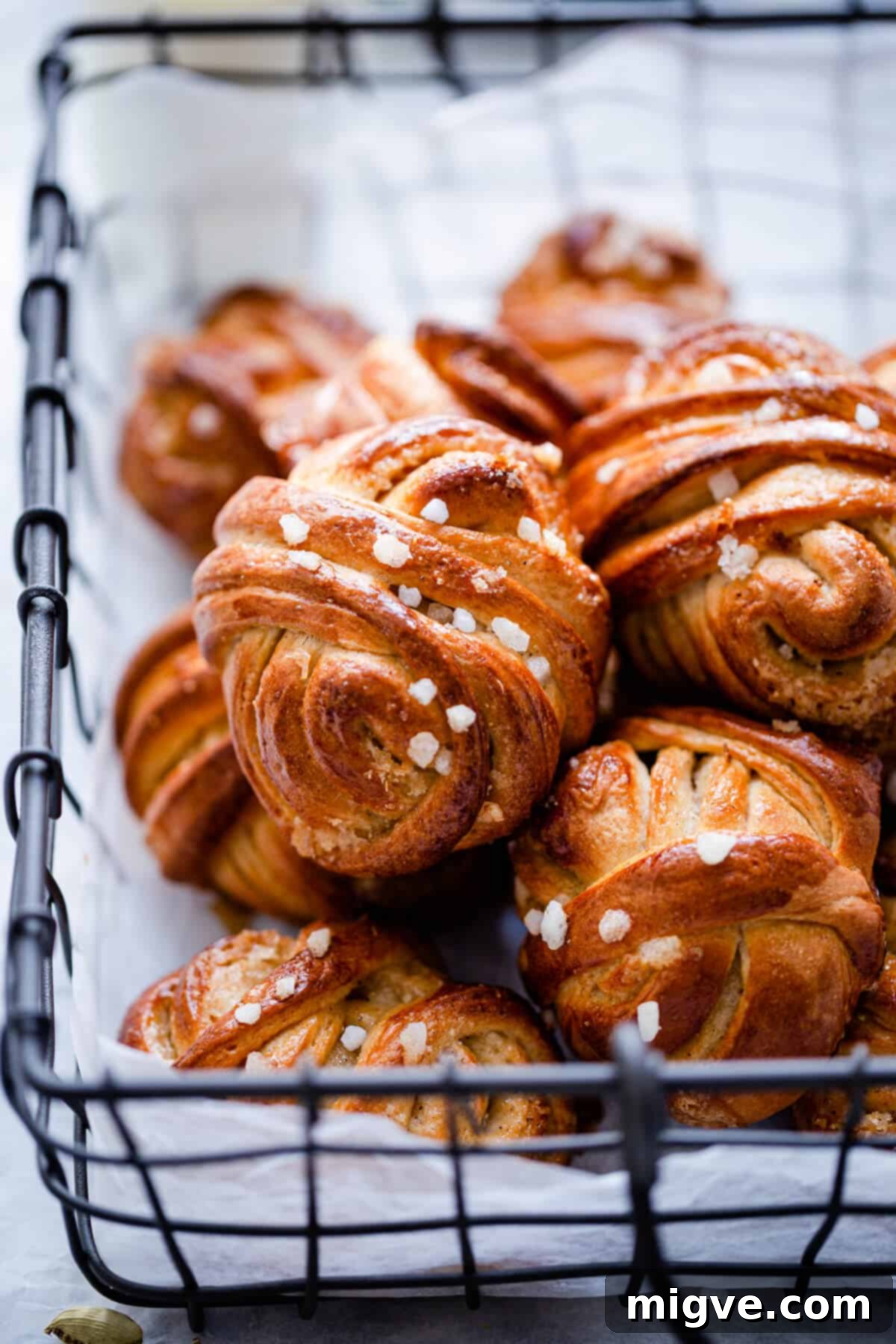 A close-up side view of several cardamom buns, showcasing their golden crust and delicate sugar pearl topping.