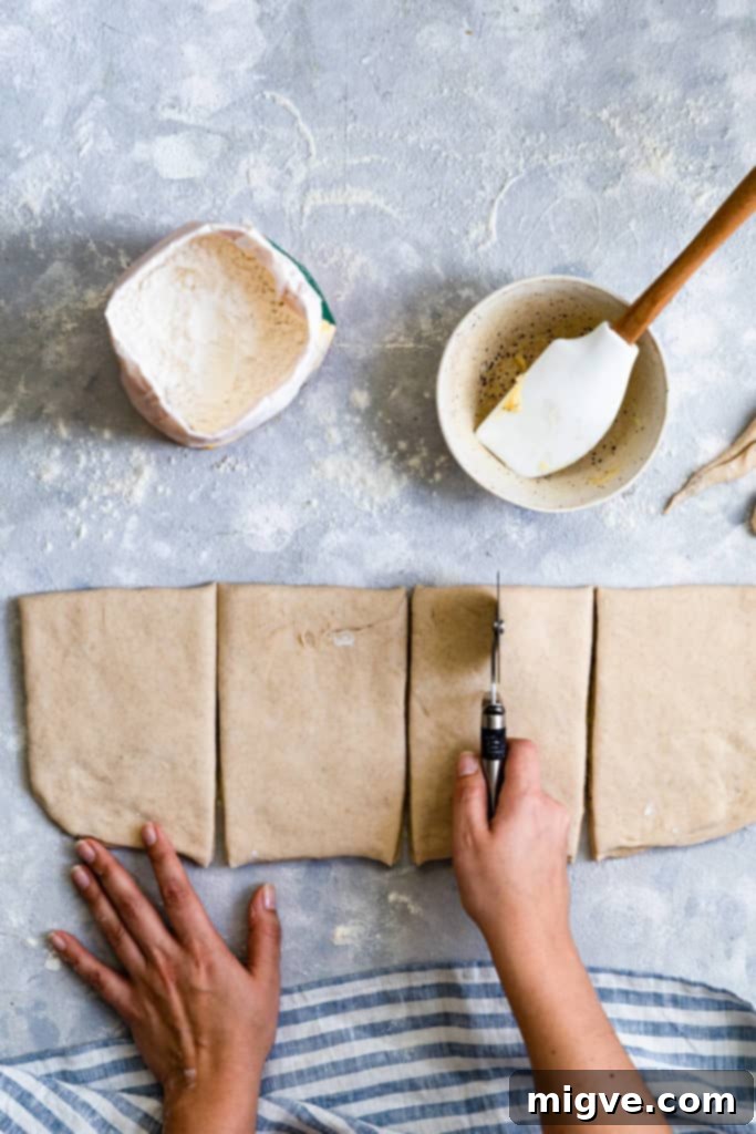 Top-down view of a person expertly slicing the folded dough with a pizza cutter.