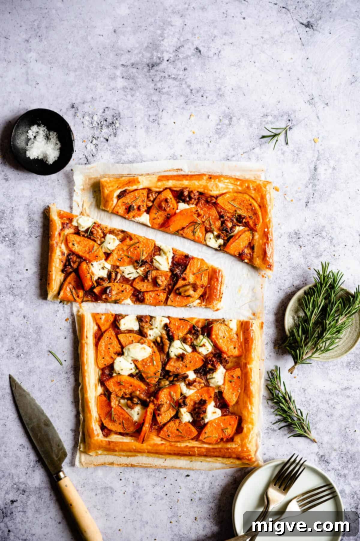 Overhead view of a savoury tart, freshly sliced into neat portions, revealing the layers of butternut squash, goats' cheese, and golden pastry.