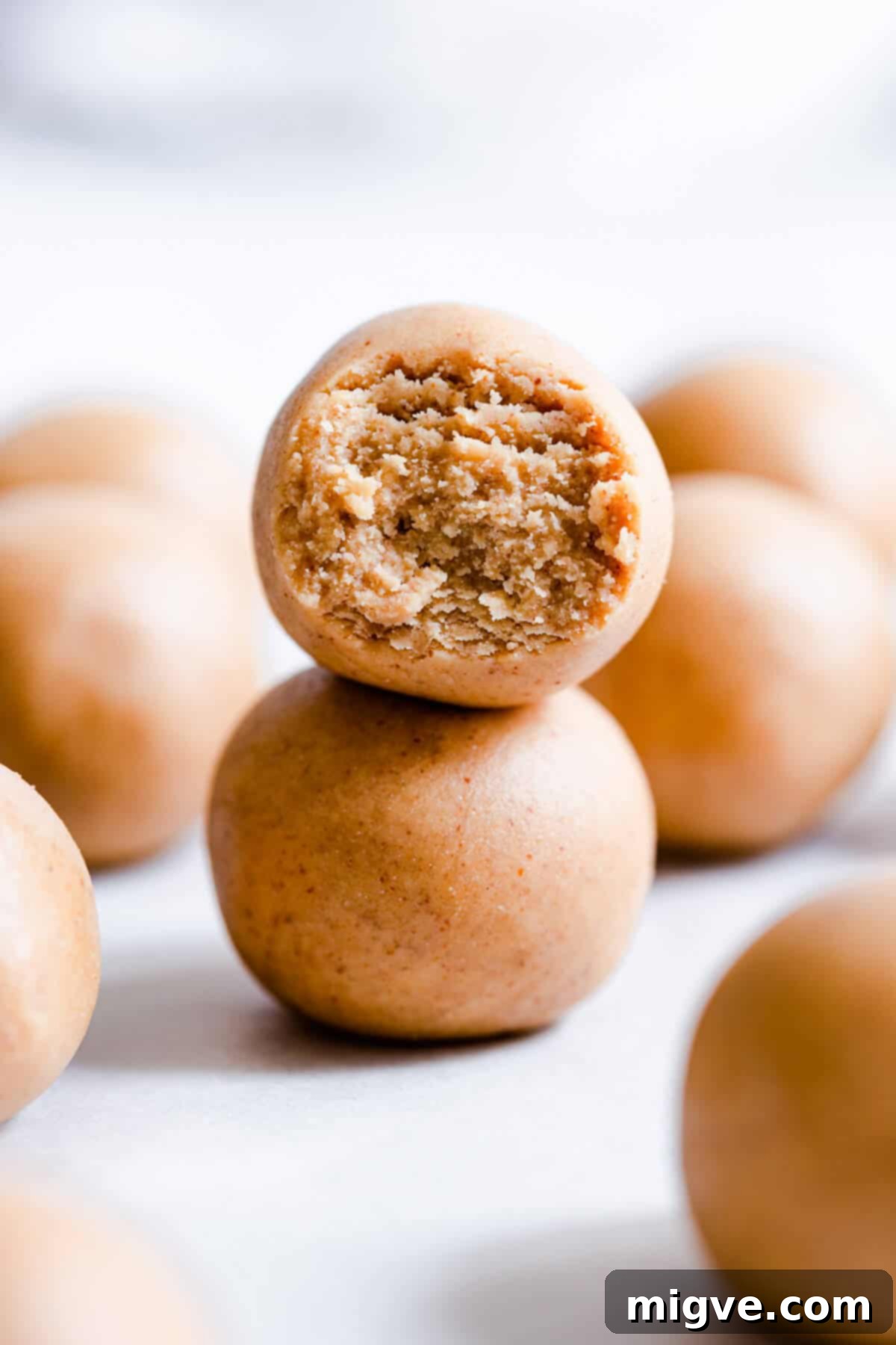 Two soft, fudgy peanut butter energy balls stacked on a white plate, showcasing their delightful texture and readiness to be enjoyed.