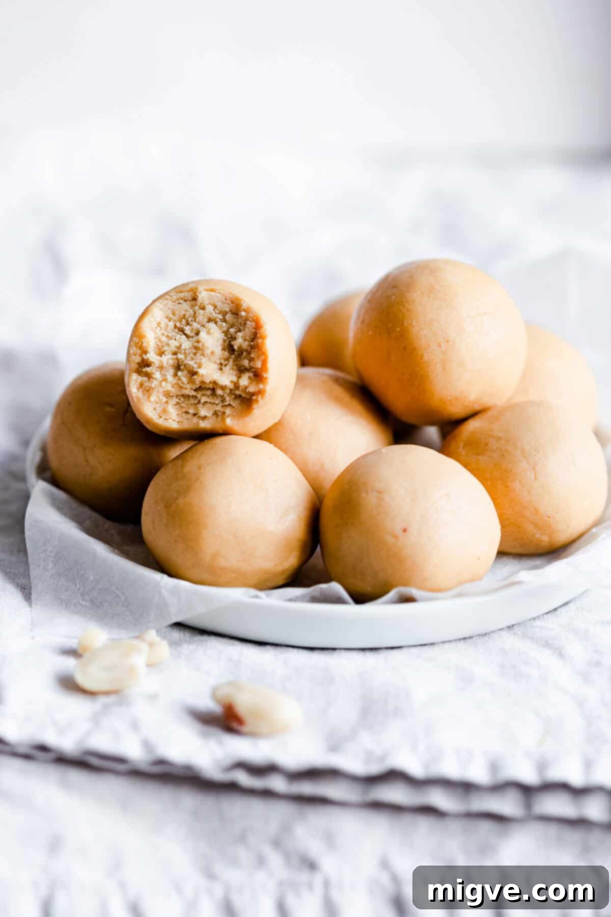 A side angle close-up of several perfectly round peanut butter energy balls neatly arranged on a small rustic plate, inviting a bite.