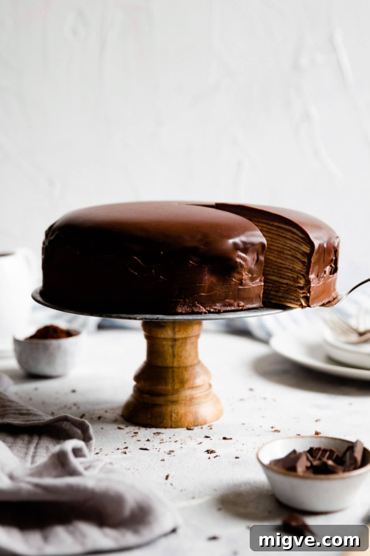 Decadent Chocolate Crepe Dream 12 side view at layered crepe cake with slice being cut out