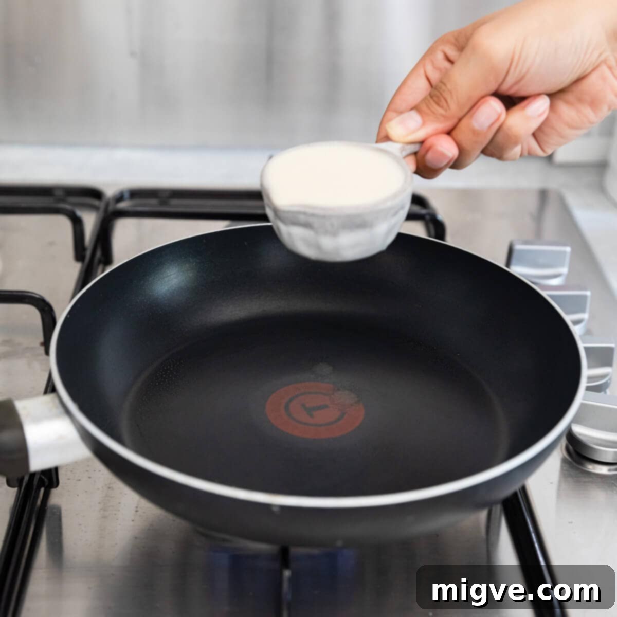 Decadent Chocolate Crepe Dream 4 side view of crepe batter in a measuring cup above frying pan