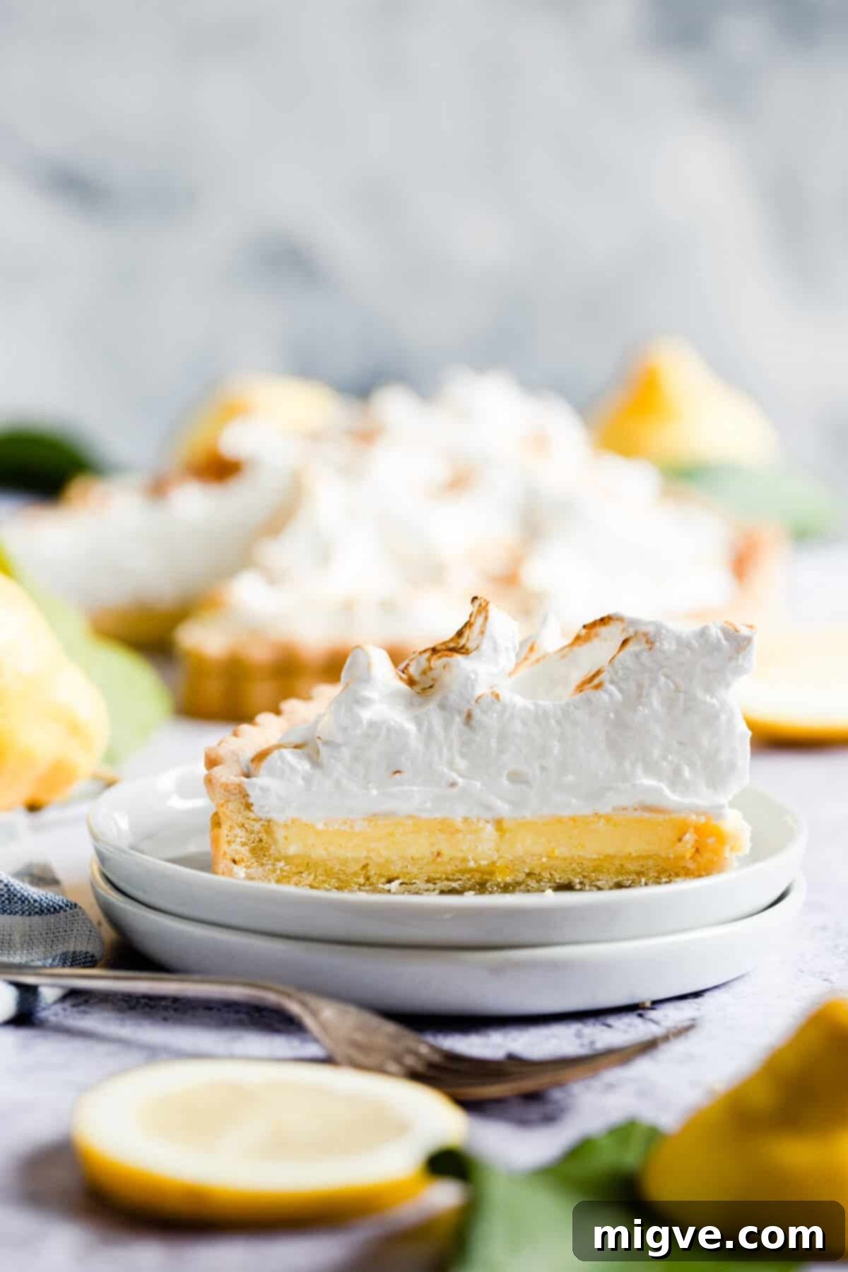 A close-up side view of an individual slice of lemon meringue pie, perfectly plated to highlight its layers and textures.