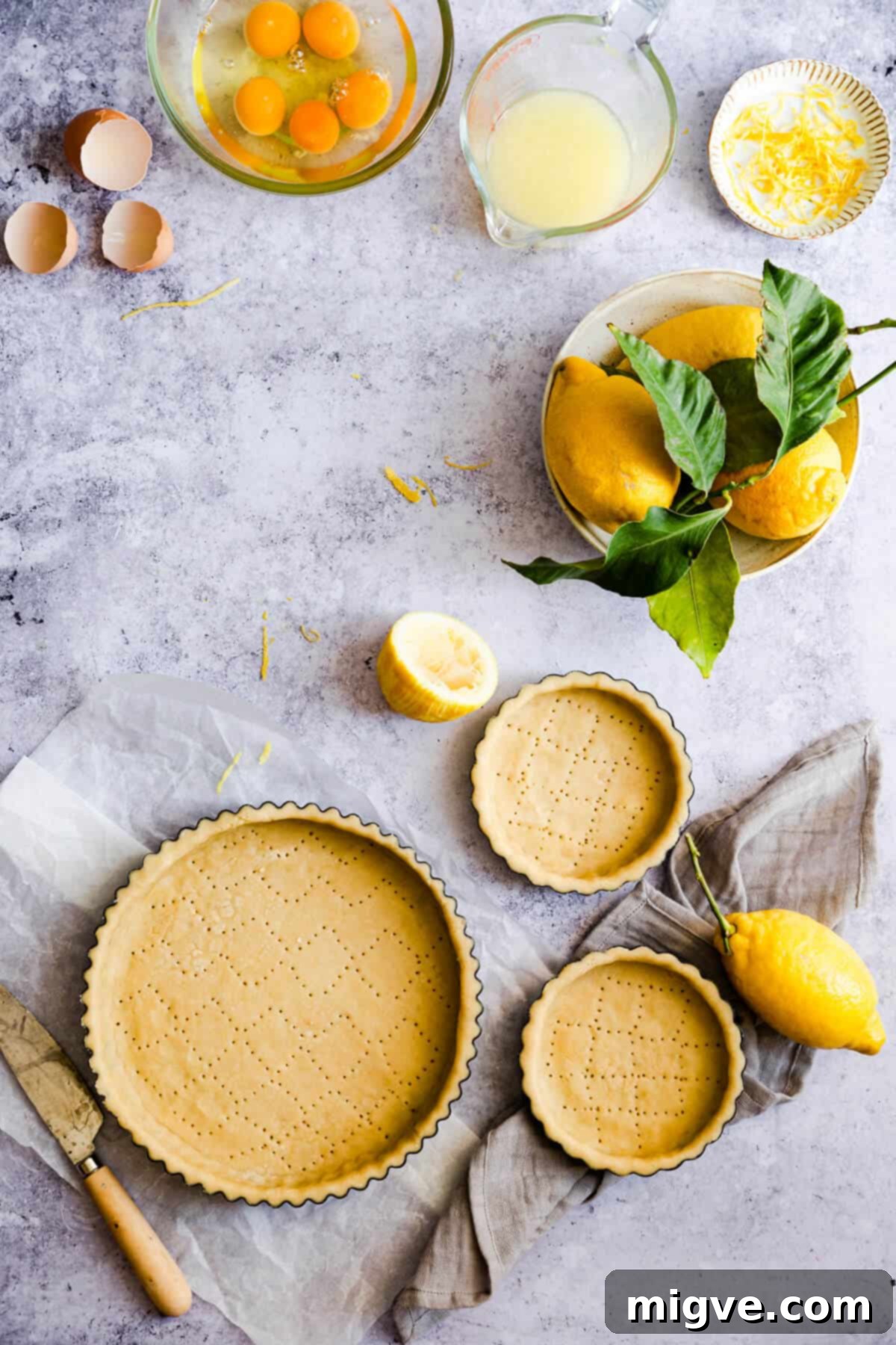 An overhead shot of unbaked pastry dough lining several round baking tins, meticulously prepared and ready for the next step in pie making.