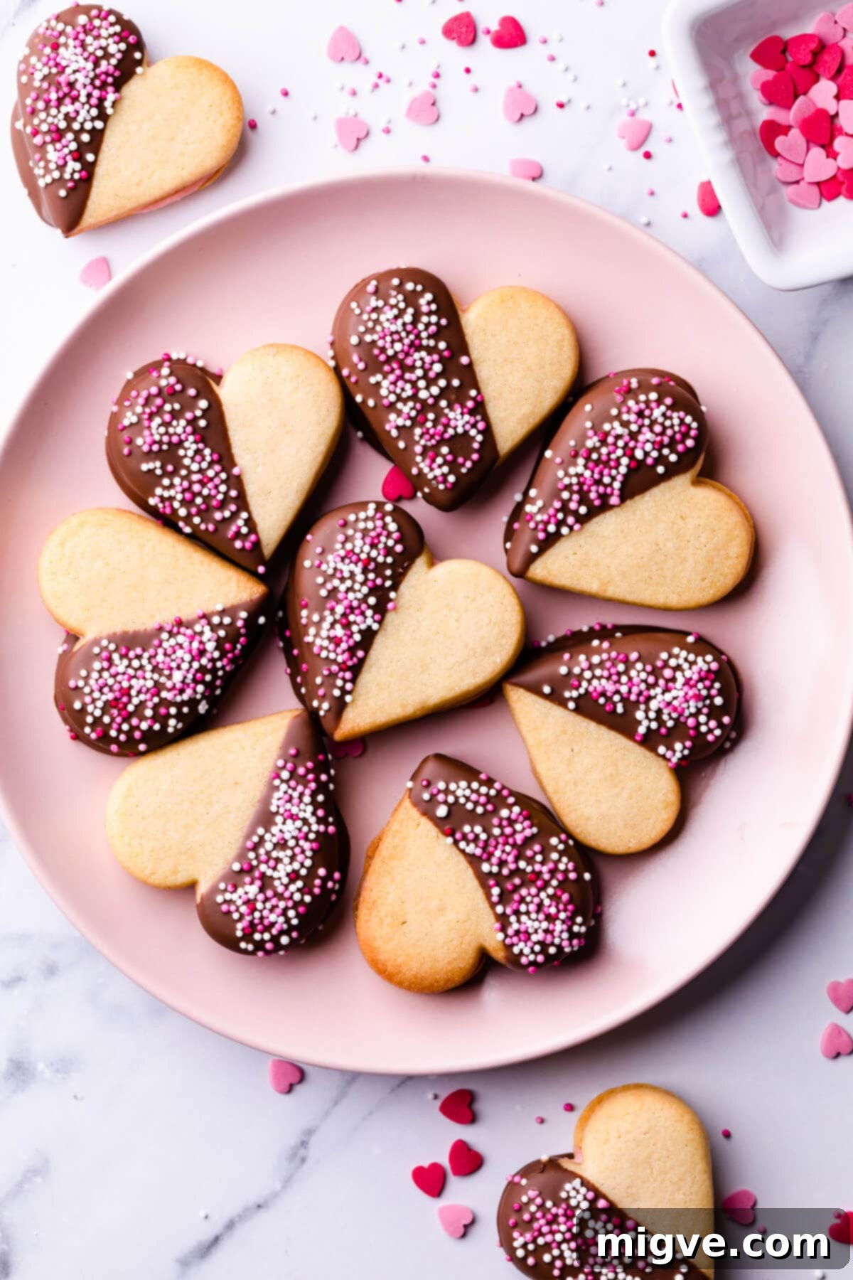 Sweetheart Sugar Cookies 11 A stack of heart-shaped sugar cookies, unfrosted, on a pink plate, ready for filling.