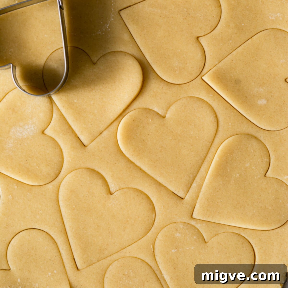 Sweetheart Sugar Cookies 4 Sugar cookie dough with heart-shaped cut-outs arranged on parchment paper.