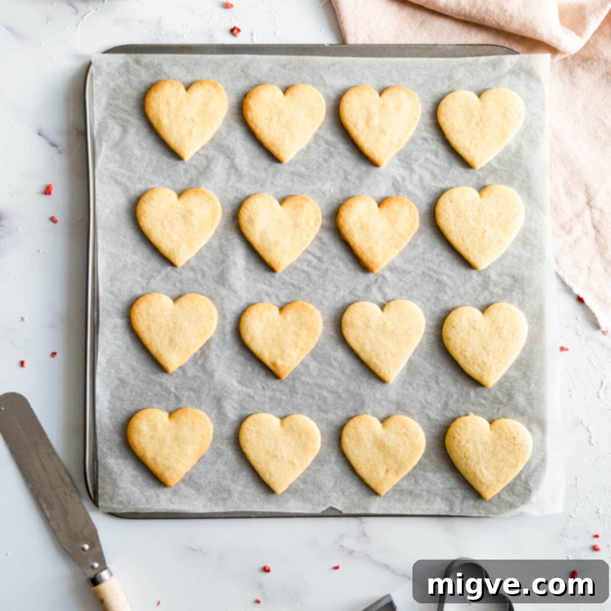Sweetheart Sugar Cookies 5 A baking sheet filled with perfectly baked Valentine sugar cookies, golden at the edges.