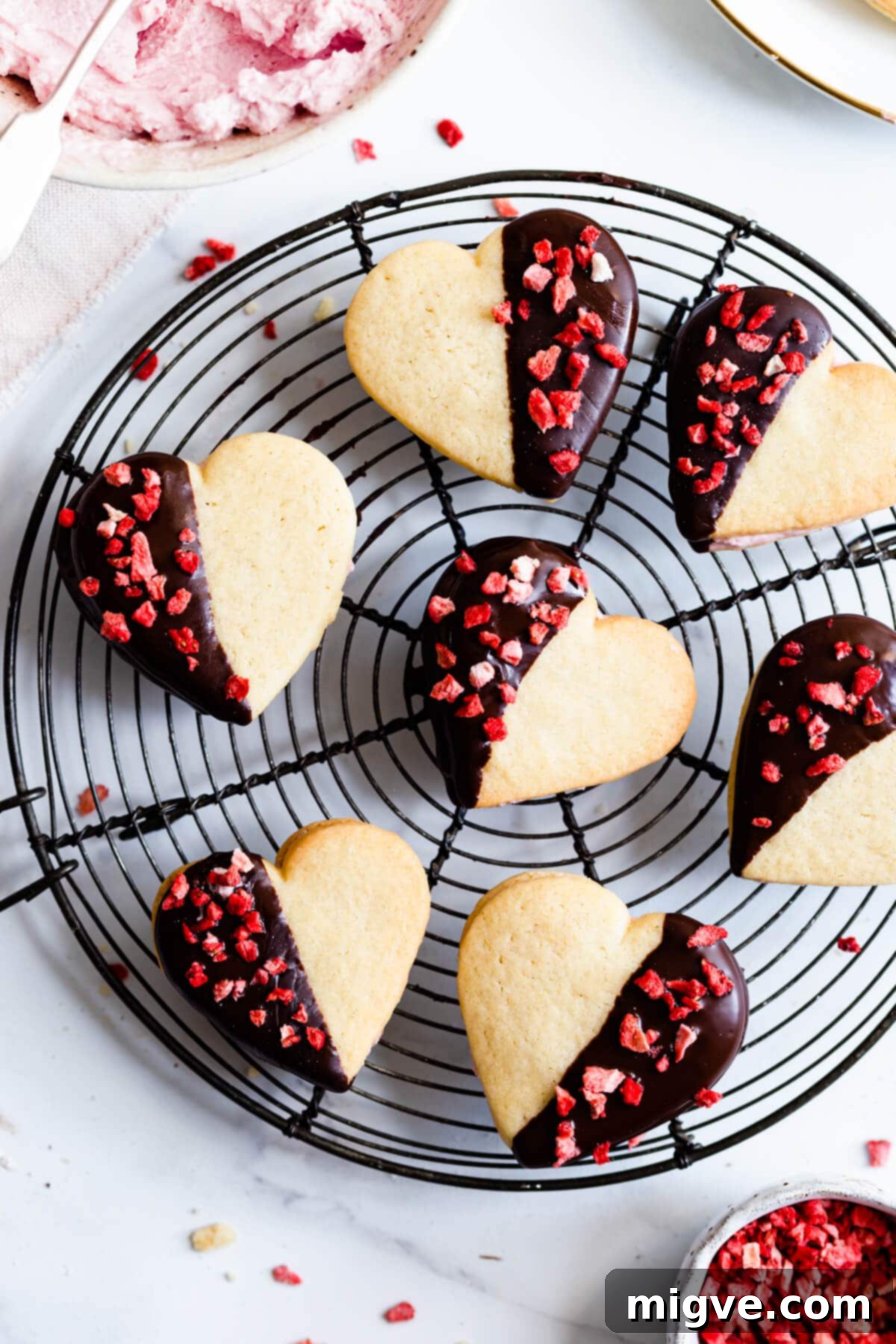 Sweetheart Sugar Cookies 10 Valentine sugar cookies cooling on a metal rack, showing their delicate heart shapes.