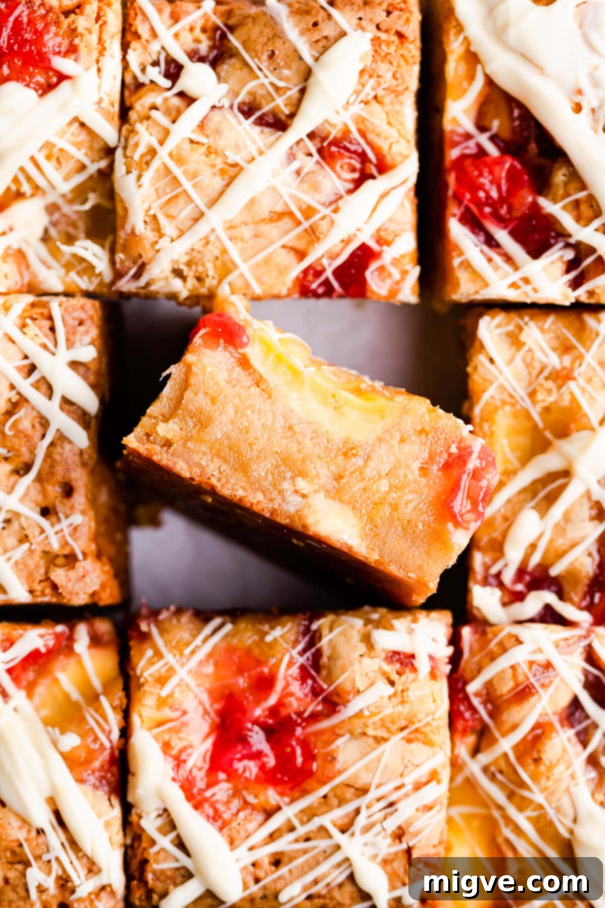 Top view close-up of a single slice of rhubarb and custard blondie bar, highlighting its distinct layers of creamy custard, rhubarb compote, and white chocolate chunks in a fudgy base.