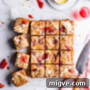 Top view of square slices of blondies topped with rhubarb and custard, showcasing the delicious swirl.