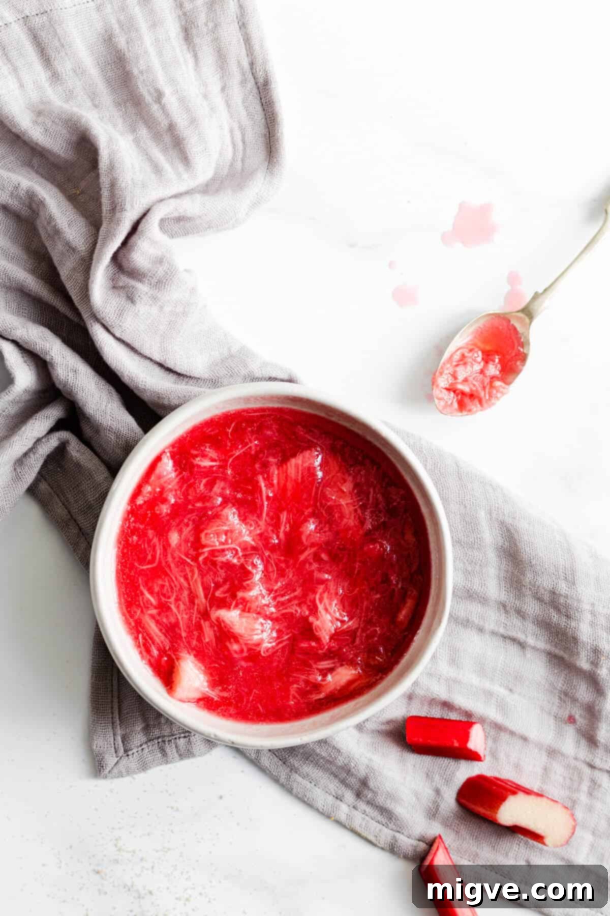 Top view close-up of a bowl filled with vibrant, homemade rhubarb compote, cooked down to a jammy consistency, ready for the blondie topping.