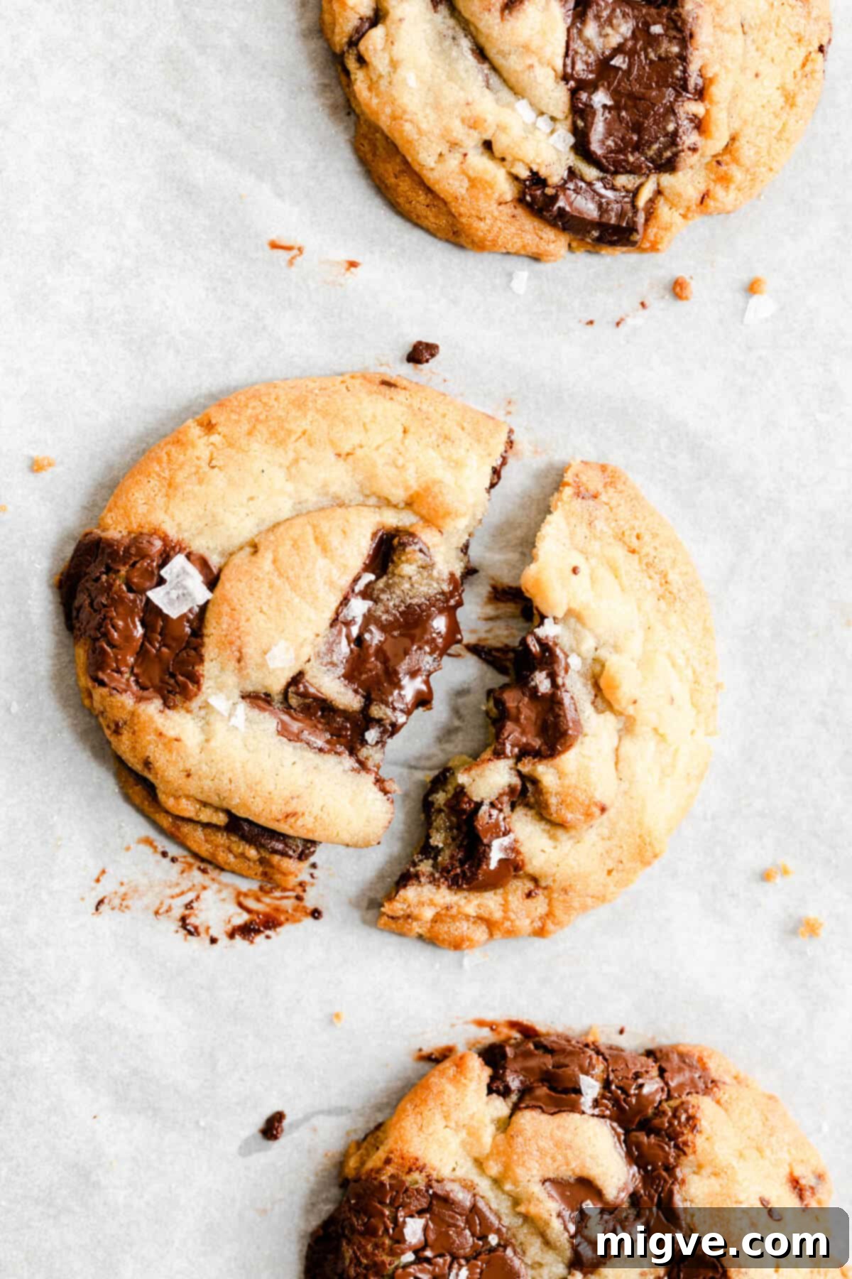 close up of a chocolate chip cookie broken in half revealing molten chocolate inside