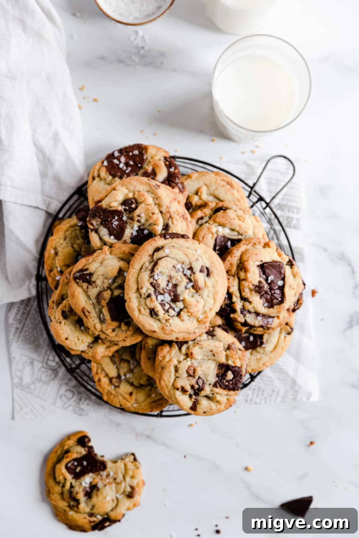 overhead shot of chocolate chip cookies on a round wire rack with a glass of milk
