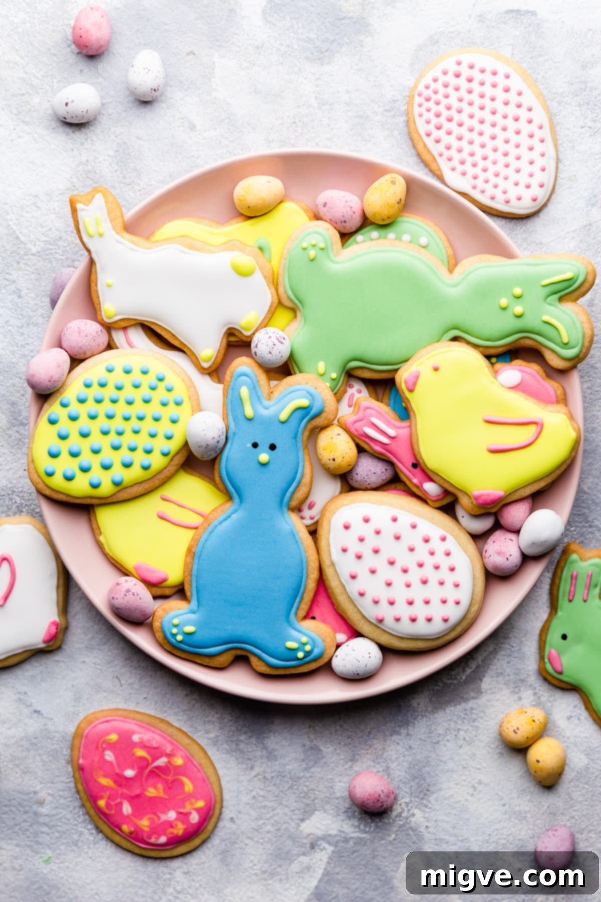 An inviting overhead shot of colorful sugar cookies, some decorated with royal icing, artfully arranged on a pristine white plate.