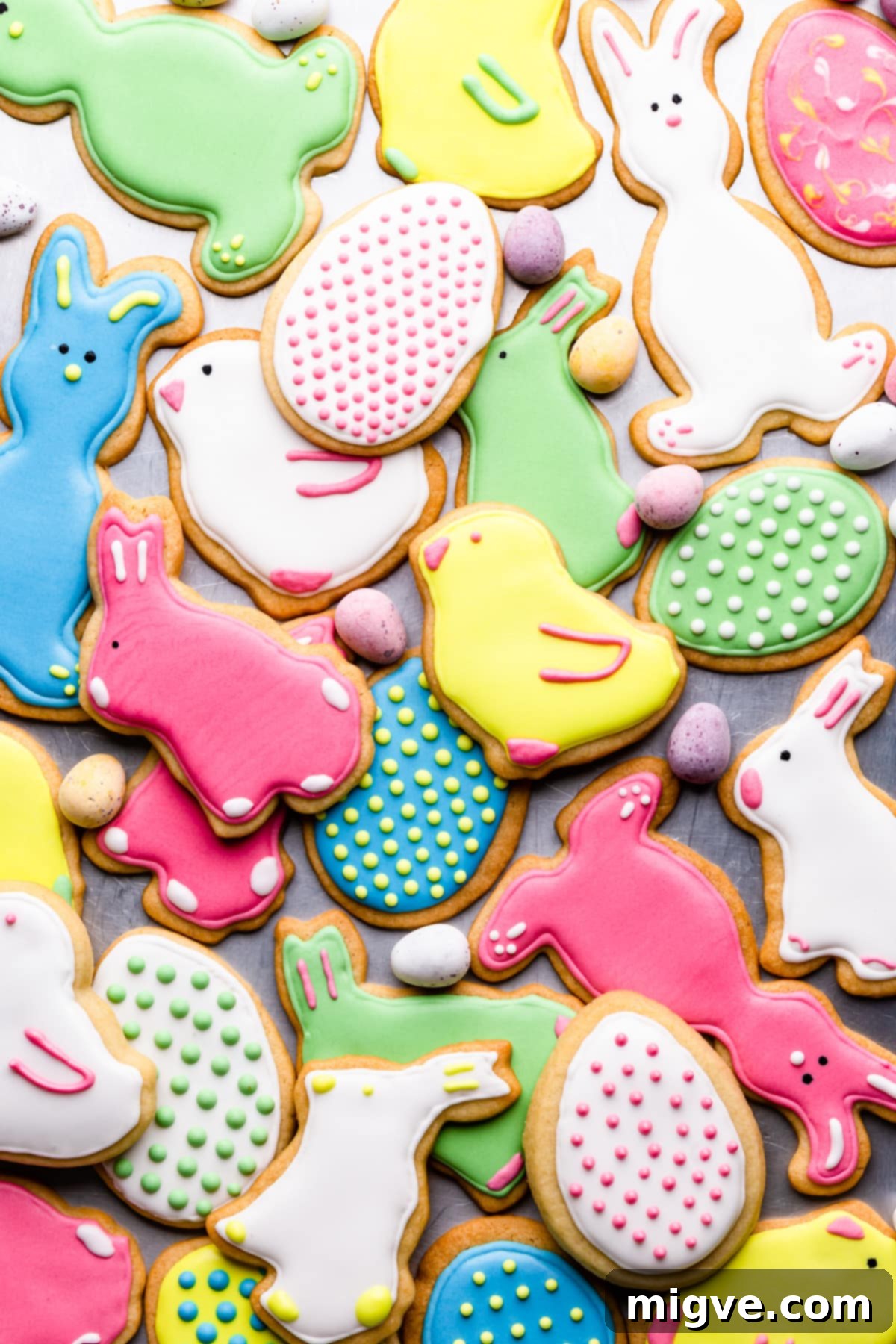 A vibrant top view of various sugar cookies meticulously decorated with colorful royal icing, showcasing different Easter-themed shapes and designs.