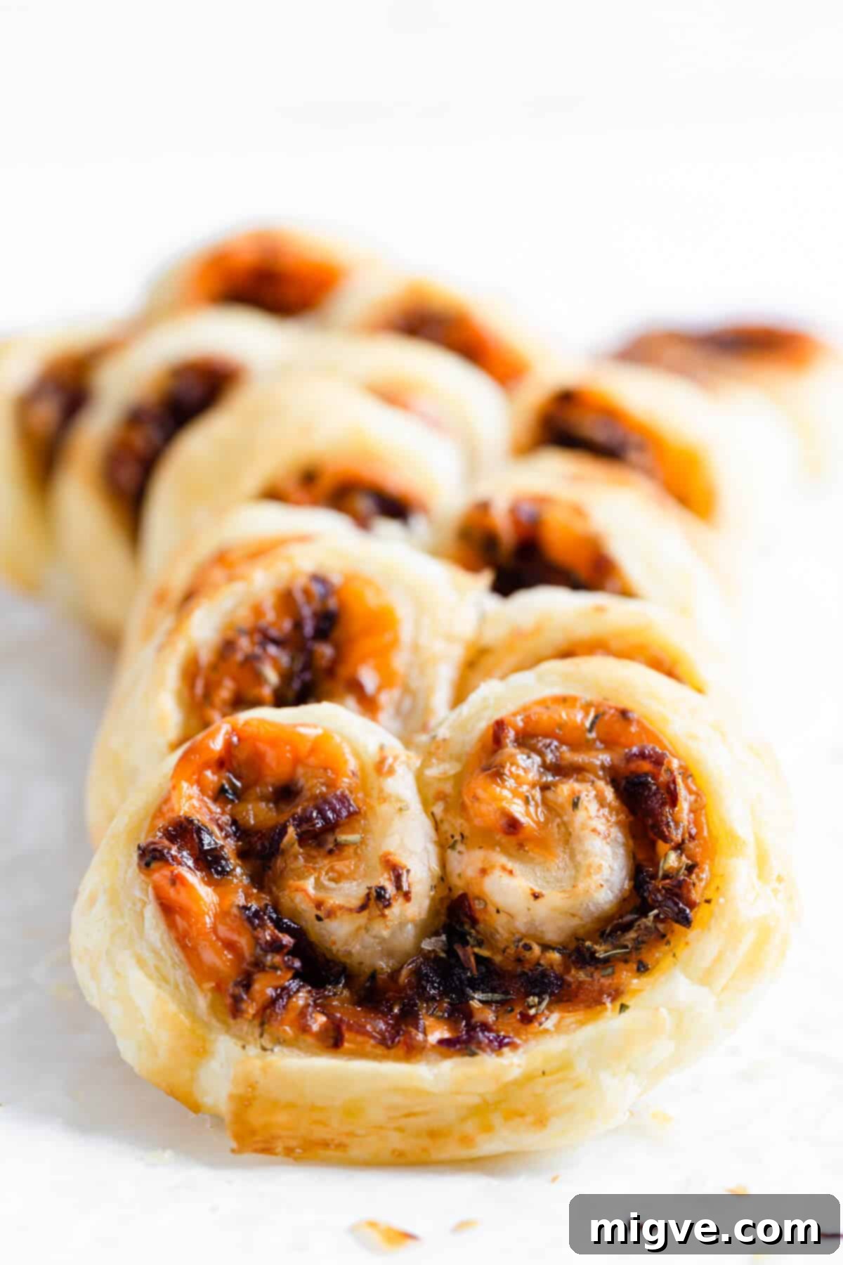 super close up of cream cheese and caramelised onion palmiers on white surface