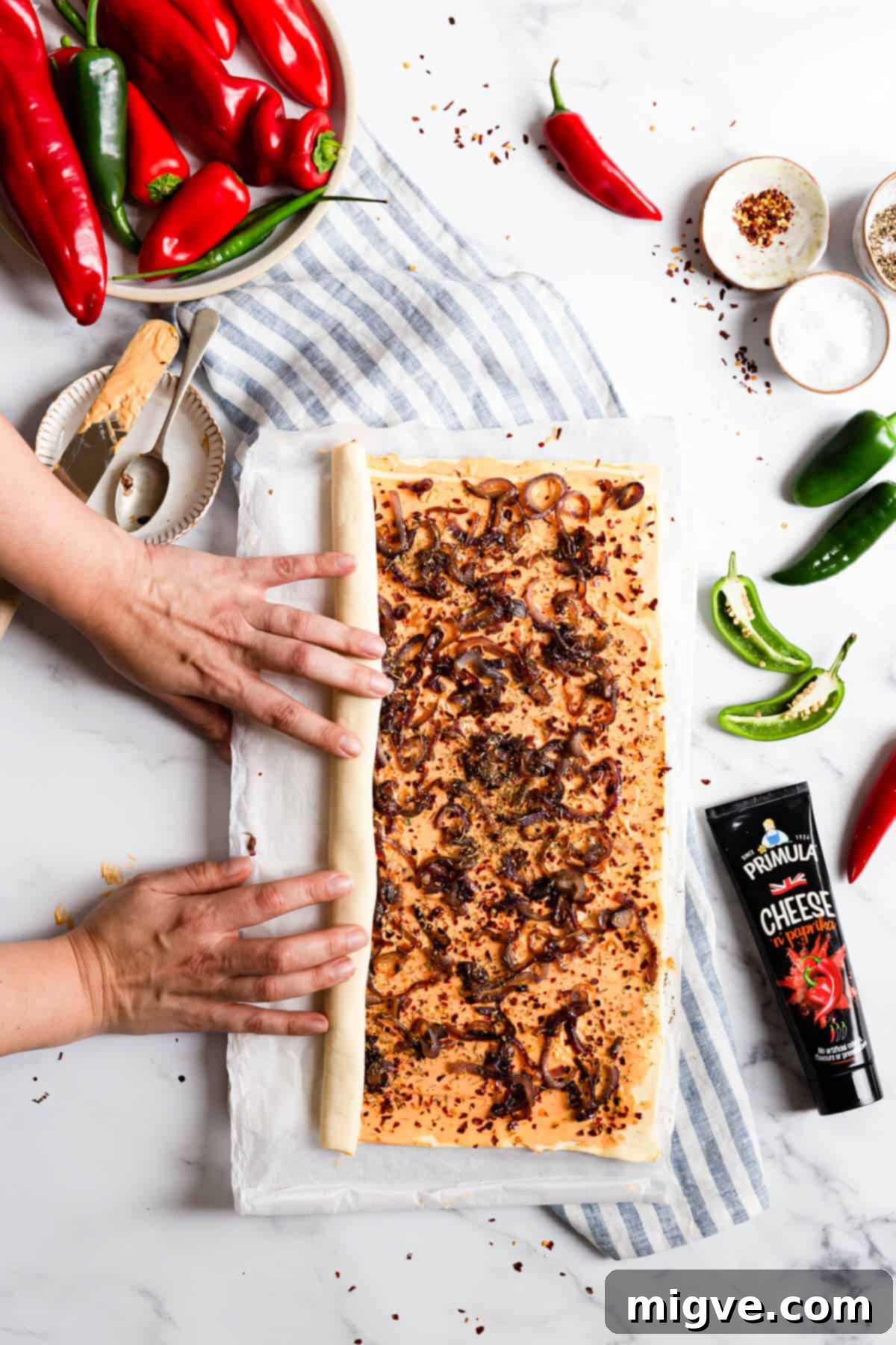 top view of a person rolling one side of puff pastry sheet